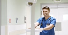 Nurse smiles as he moves NOVA MCA 20L solution across hallway